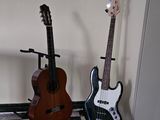 two guitars sitting on a stand in the corner of a room