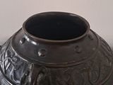a black vase sitting on a table with a white wall in the background