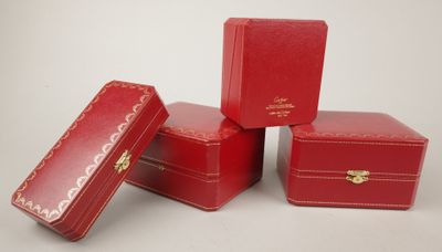 quatre coffrets en cuir rouge ornés de ferrures dorées, posés sur une surface blanche