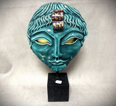 un gros plan sur une sculpture représentant le visage d'une femme avec une fleur sur la tête