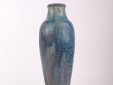 un vase bleu posé sur une surface blanche