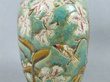 un vase vert orné d'oiseaux et de fleurs