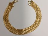 a close up of a gold chain bracelet on a white surface
