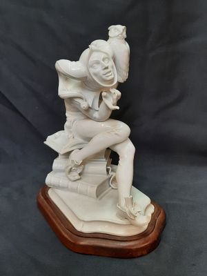 une statue blanche représentant une femme assise sur un livre