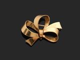 a close up of a gold bow brooch on a black background