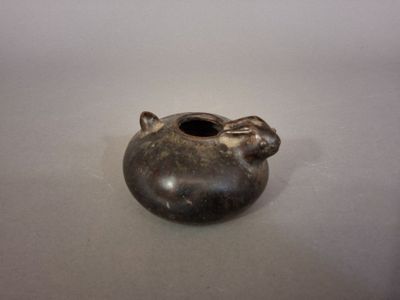 a small vase with a cat on it sitting on a table