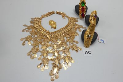 un collier en or, des boucles d'oreilles et une bague posés sur une table