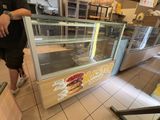 un homme debout devant un comptoir sur lequel est posé un sandwich