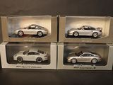 three boxed boxes of silver model cars on a black surface
