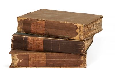 trois vieux livres empilés sur une surface blanche