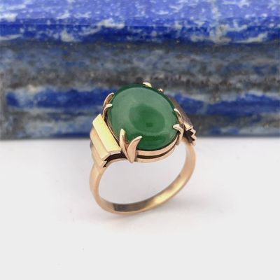 a close up of a ring with a green stone on it