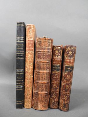 four old books are stacked on top of each other on a gray surface