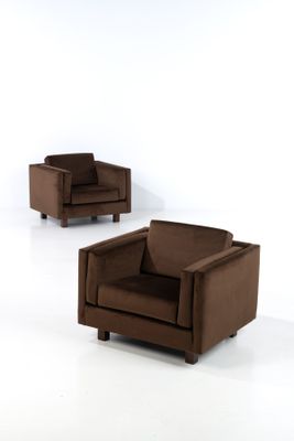 pair of brown leather chairs in a white room with a white wall