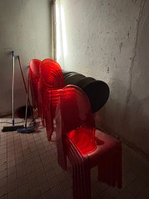 several red plastic chairs are lined up against a wall in a dark room