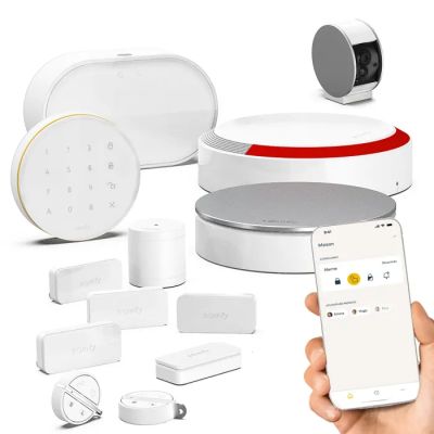 une personne tenant un smartphone devant tout un tas de gadgets