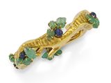 un gros plan sur une broche en or sertie de pierres vertes et bleues