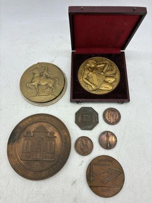 un assortiment de pièces comprenant une médaille en or, une pièce en argent et une boîte rouge