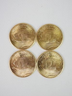 quatre pièces d'or superposées sur une surface blanche