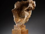a sculpture of a man ' s head on top of a wooden block