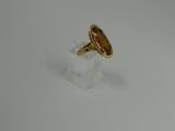 a gold ring on a clear stand on a white surface