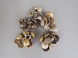 four pieces of silver and gold buttons on a white surface