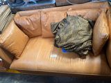 a brown leather couch with a pillow on top of it