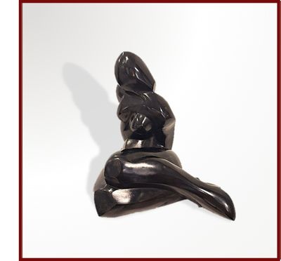 une statue noire représentant une femme assise sur une surface blanche