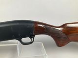 a close up of a rifle on a clear stand on a white surface