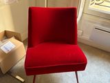 une chaise rouge dans une pièce où se trouve une boîte par terre
