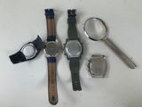 three watches and a magnifying glass on a white surface