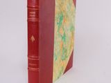 an old red book sitting on top of a table next to a white wall
