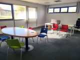 brightly colored chairs sit around a round table in an empty room