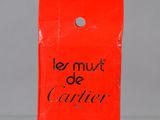 a red bag with the words le must de cartier on it