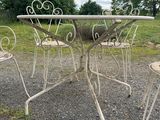 an image of a table and four chairs sitting on a gravel road