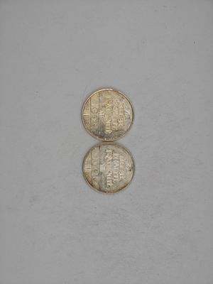 two coins sitting side by side on top of a white surface