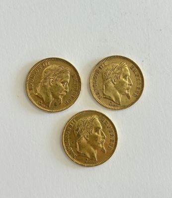 three gold sovereigns on a white surface
