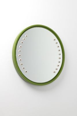 un miroir circulaire vert accroché à un mur blanc