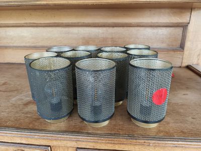 six glasses are lined up on a wooden shelf in a room
