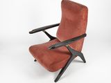 un fauteuil en velours rouge, avec des pieds noirs et une structure en bois