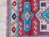 a close up of a red and blue rug on a tiled floor
