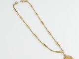 a gold necklace with a coin on a chain