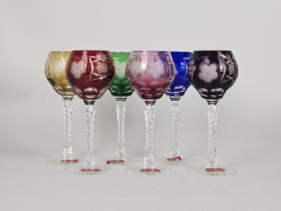 four wine glasses are lined up in a row on a white surface