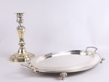 un plateau en argent avec une bougie et une assiette en argent posés sur une table