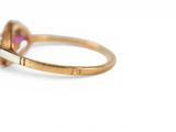 an image of a close up of a gold ring with a pink stone