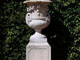 a large white vase sitting on a pedestal in the middle of the grass