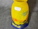 un vase jaune au pied bleu posé sur une surface grise