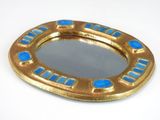 a gold and blue mirror sitting on a white surface