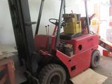 un chariot élévateur rouge dans un entrepôt, chargé de cartons