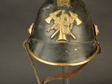 an old helmet with a gold emblem on it sitting on a stand