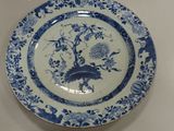 a blue and white plate with a bird and flowers on it